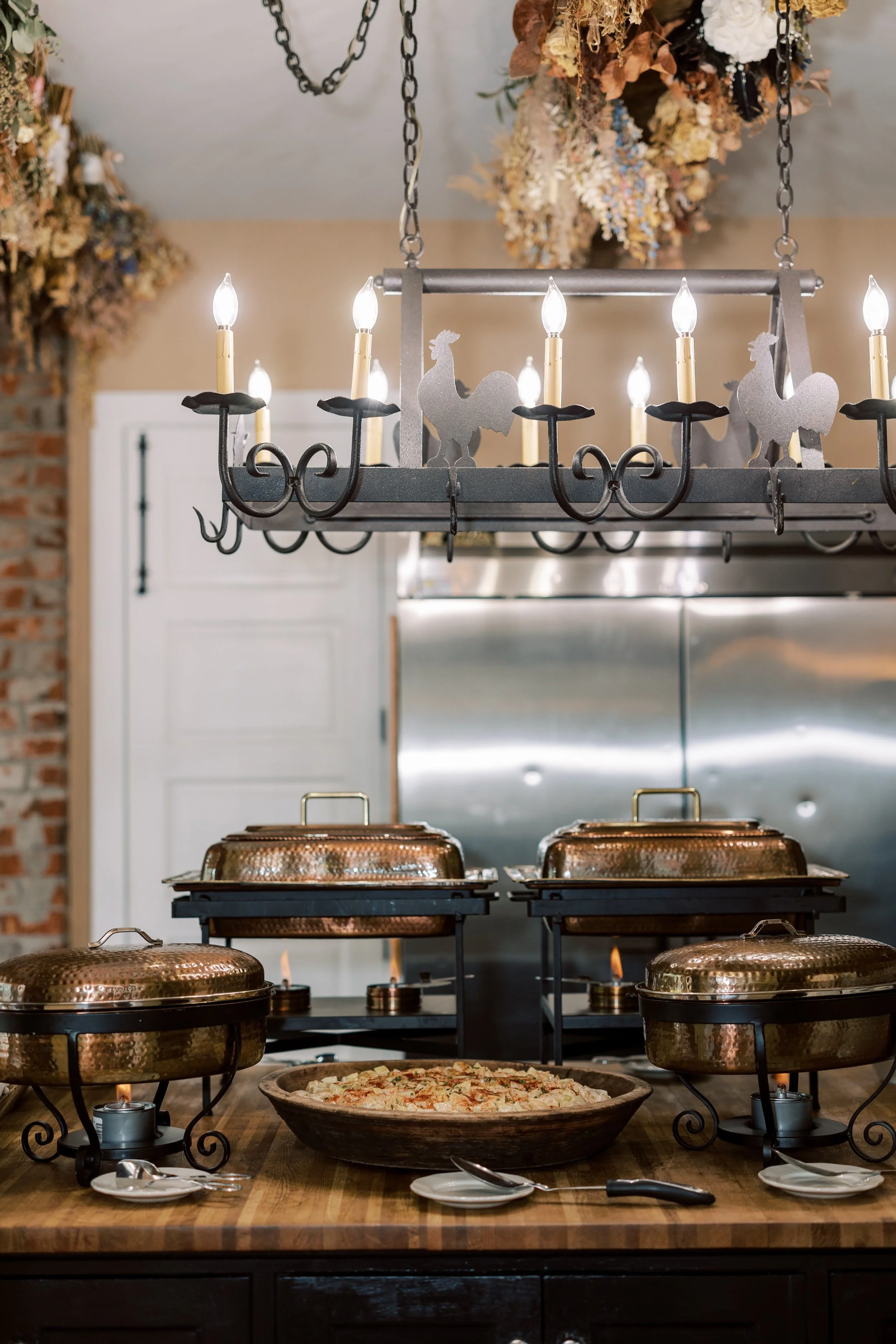 Wedding DJ standing near reception lighting and equipment inside a rustic venue