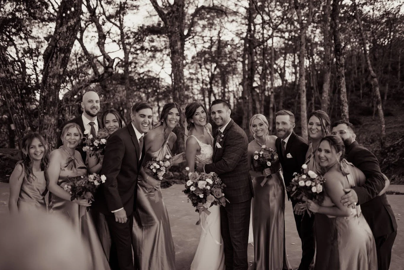 Black-and-white wedding party group portrait with the bride and groom surrounded by bridesmaids and groomsmen