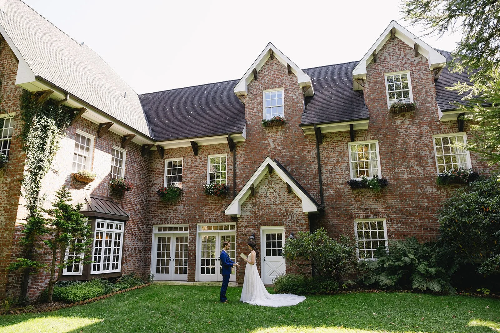 Bride and groom standing together on the lawn behind a brick estate wedding venue