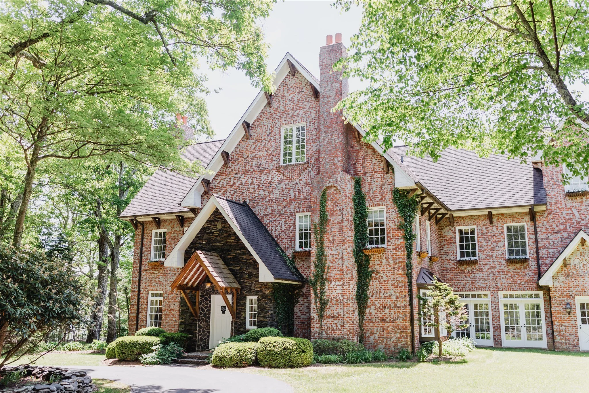 Exterior of Twickenham house wedding venue, a red brick estate with gabled roof, ivy accents, and tree-lined lawn