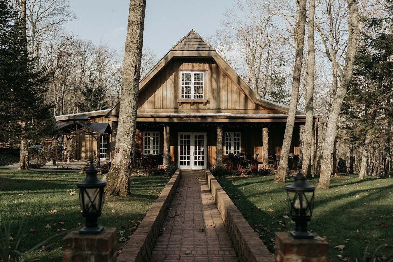 Rustic woodland cabin exterior with a brick walkway leading to double doors