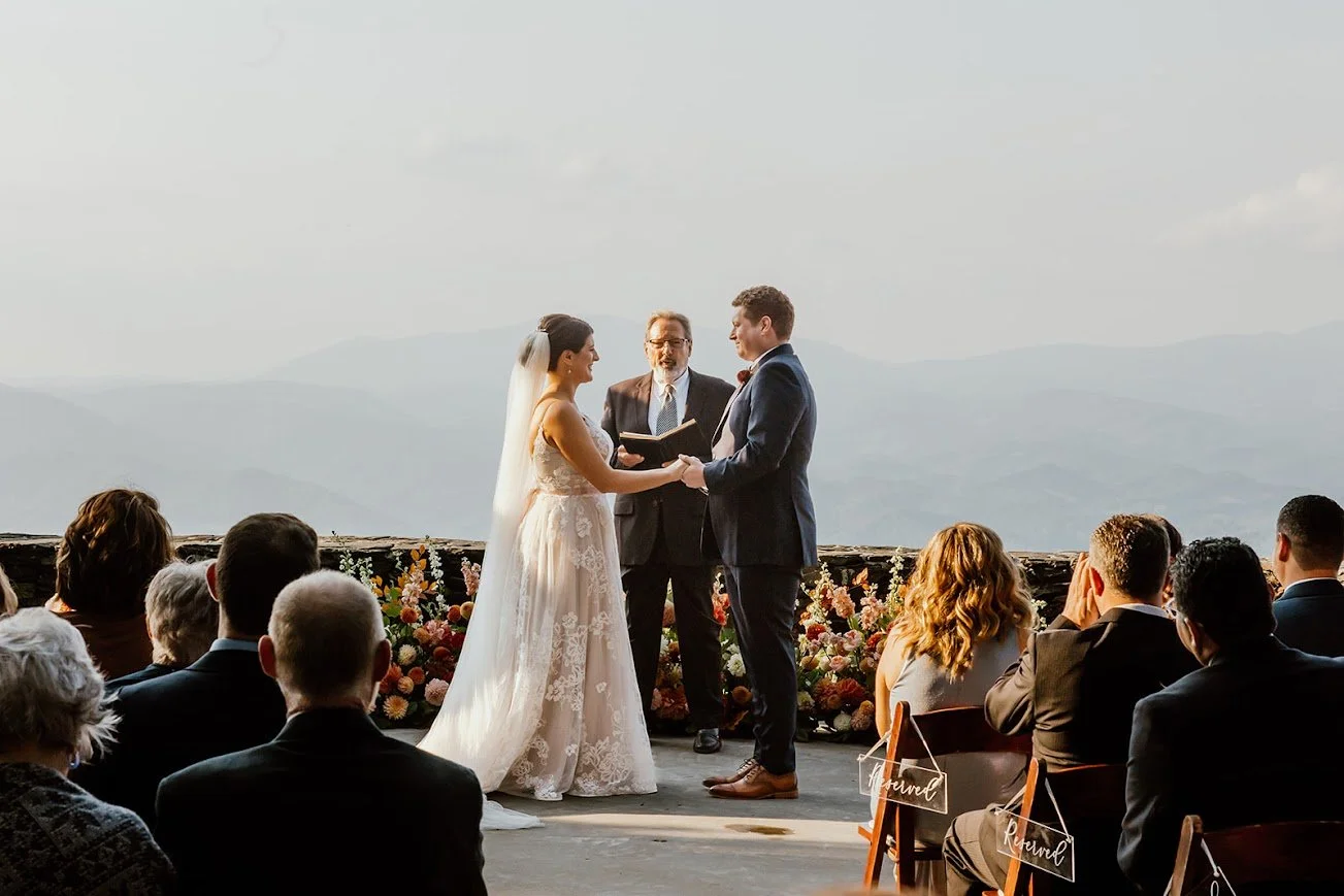 Wedding party cheering together at a mountain overlook with a circular arch backdrop
