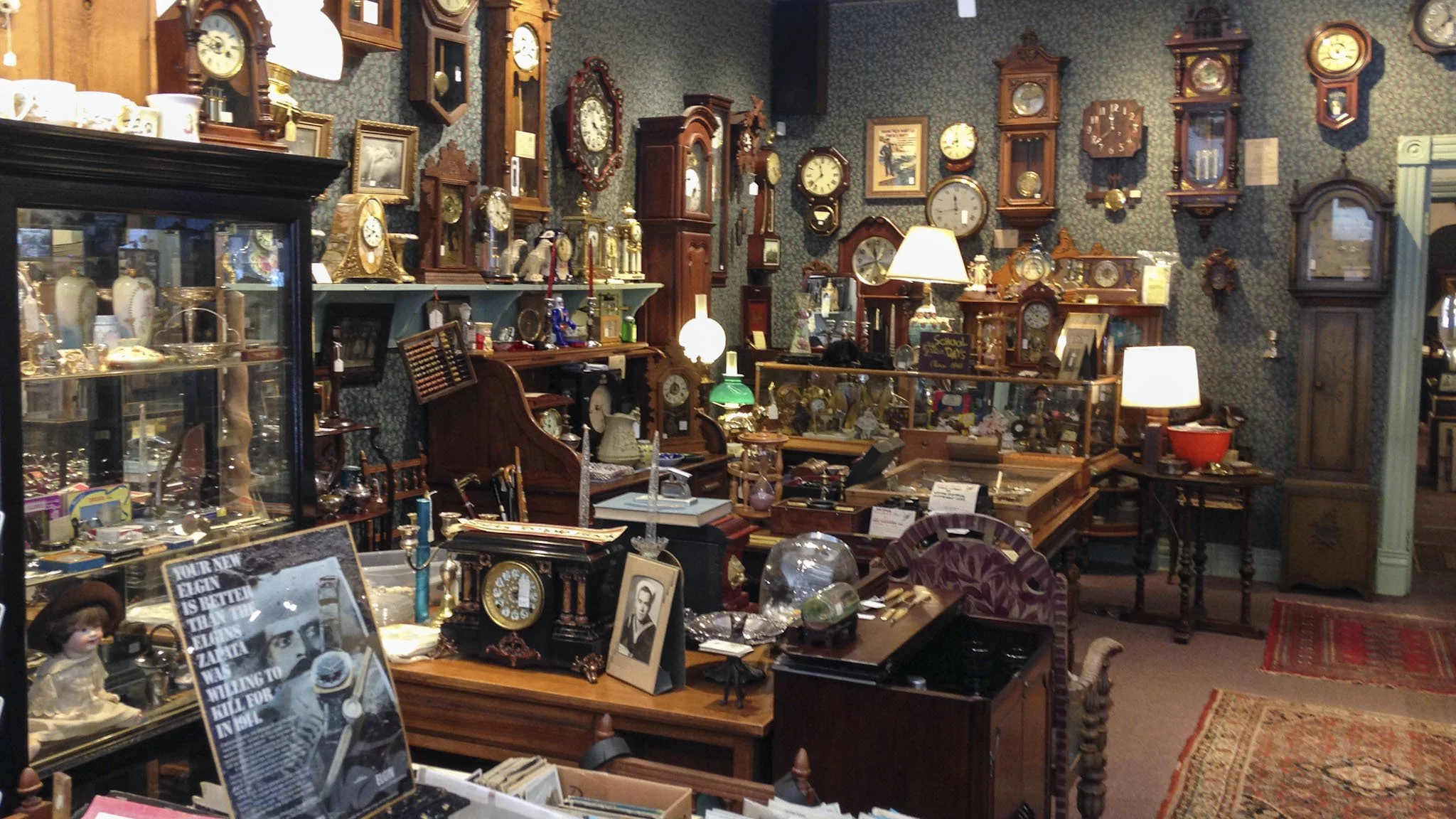 Antique store interior filled with vintage clocks, lamps, framed art, and wooden furniture.