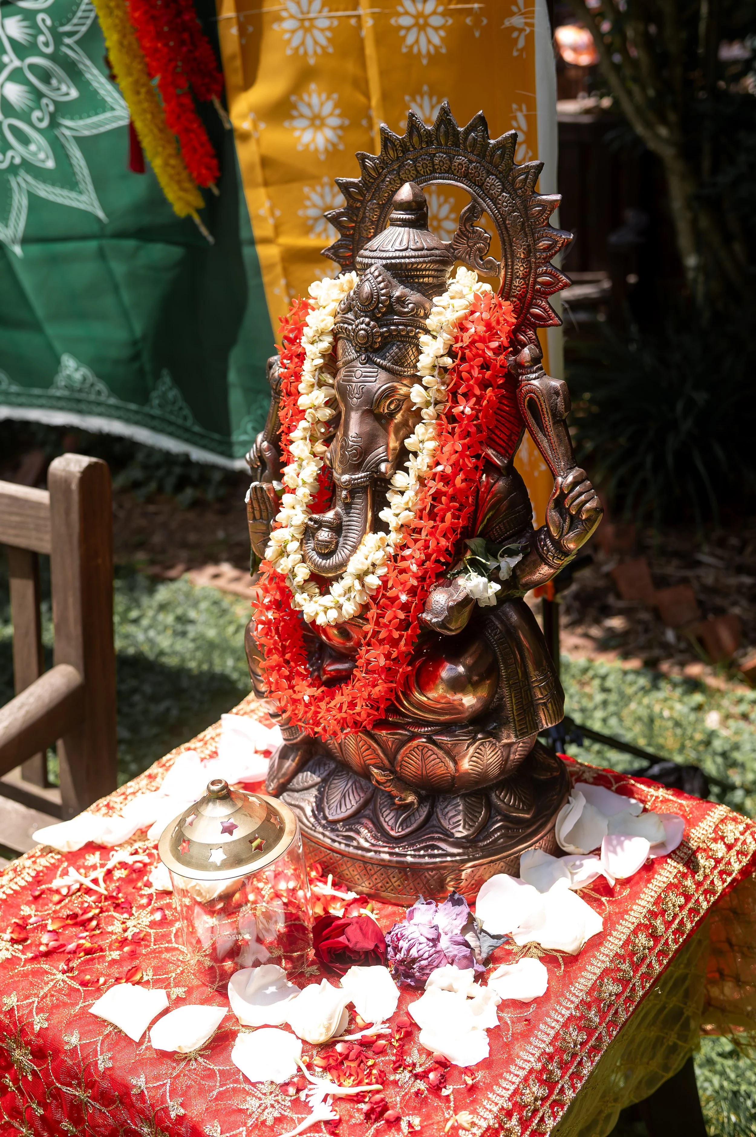 Ganesha statue decorated with red and white flower garlands for a Hindu wedding celebration.