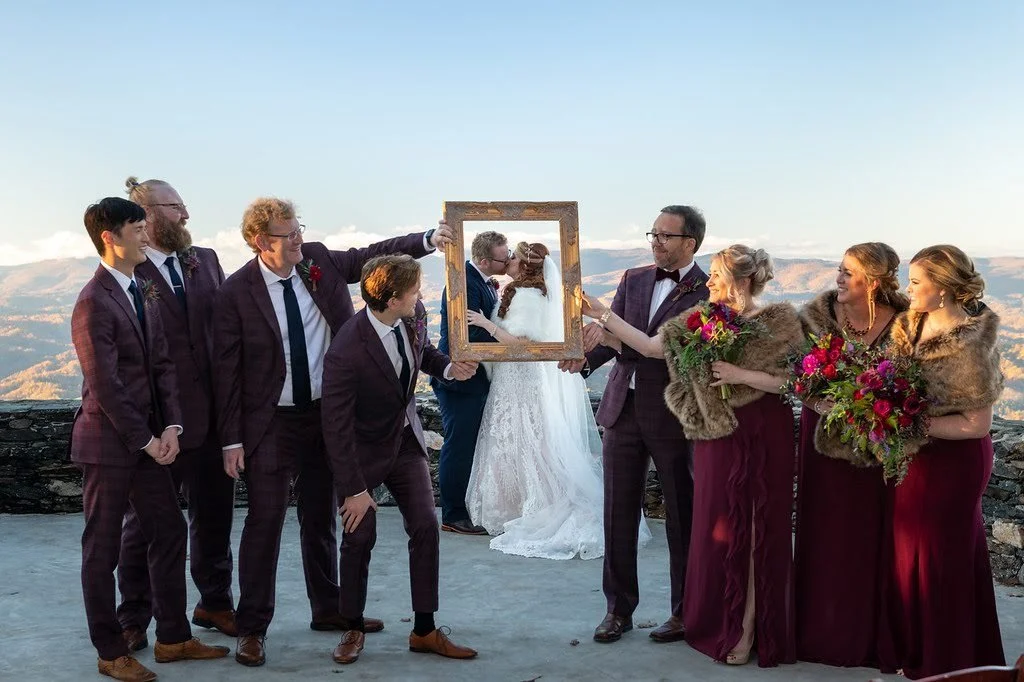 Bride standing on a rocky overlook with fall-colored mountains in the distance