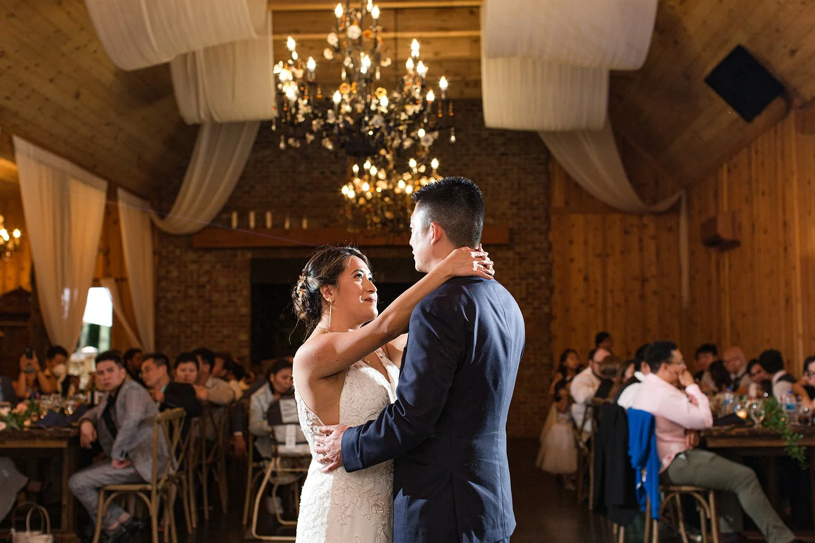 Bride and groom sharing their first dance during a rustic barn wedding reception.