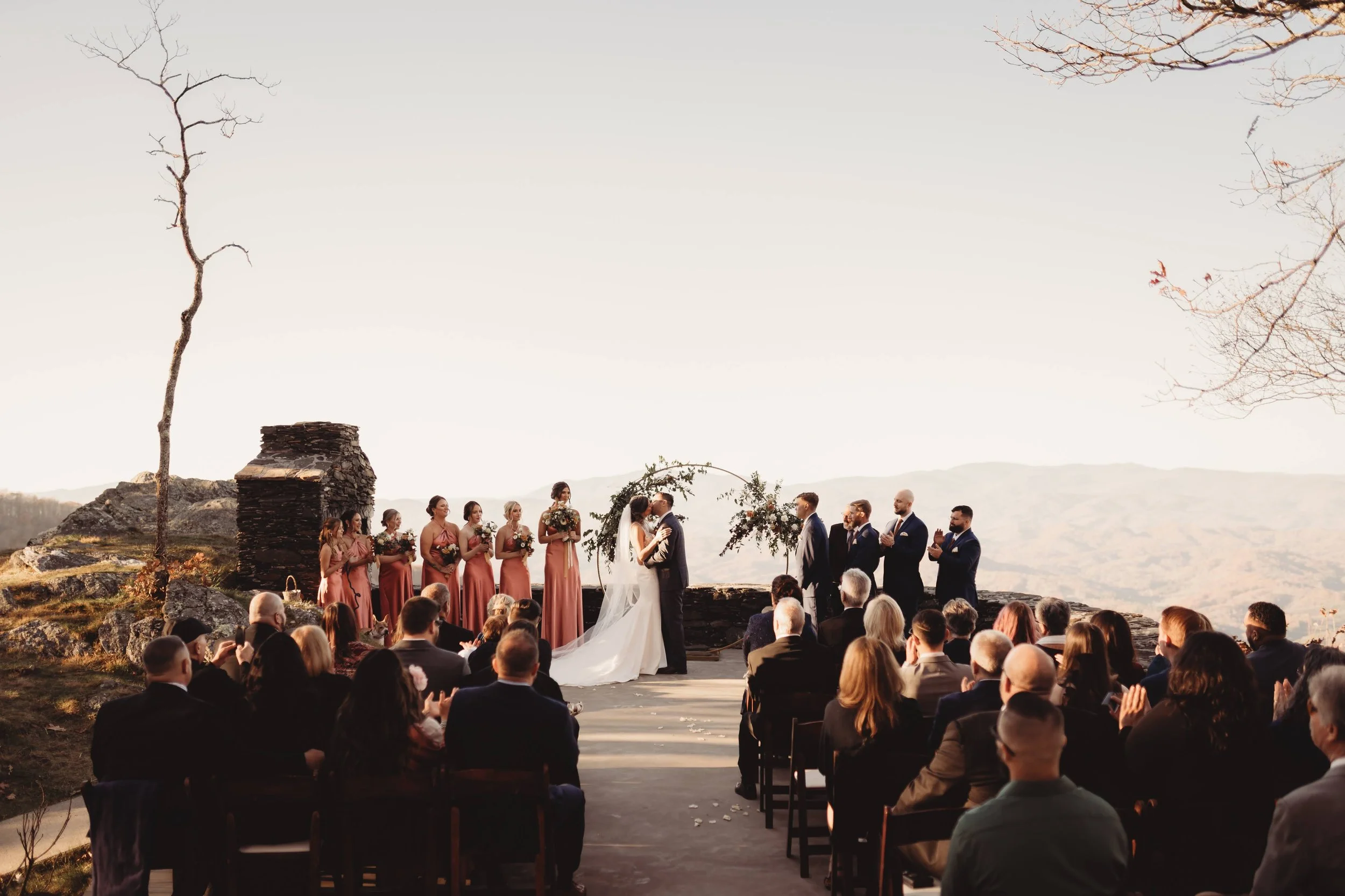 Mountaintop wedding ceremony with guests seated and a floral arch framing the couple at the altar