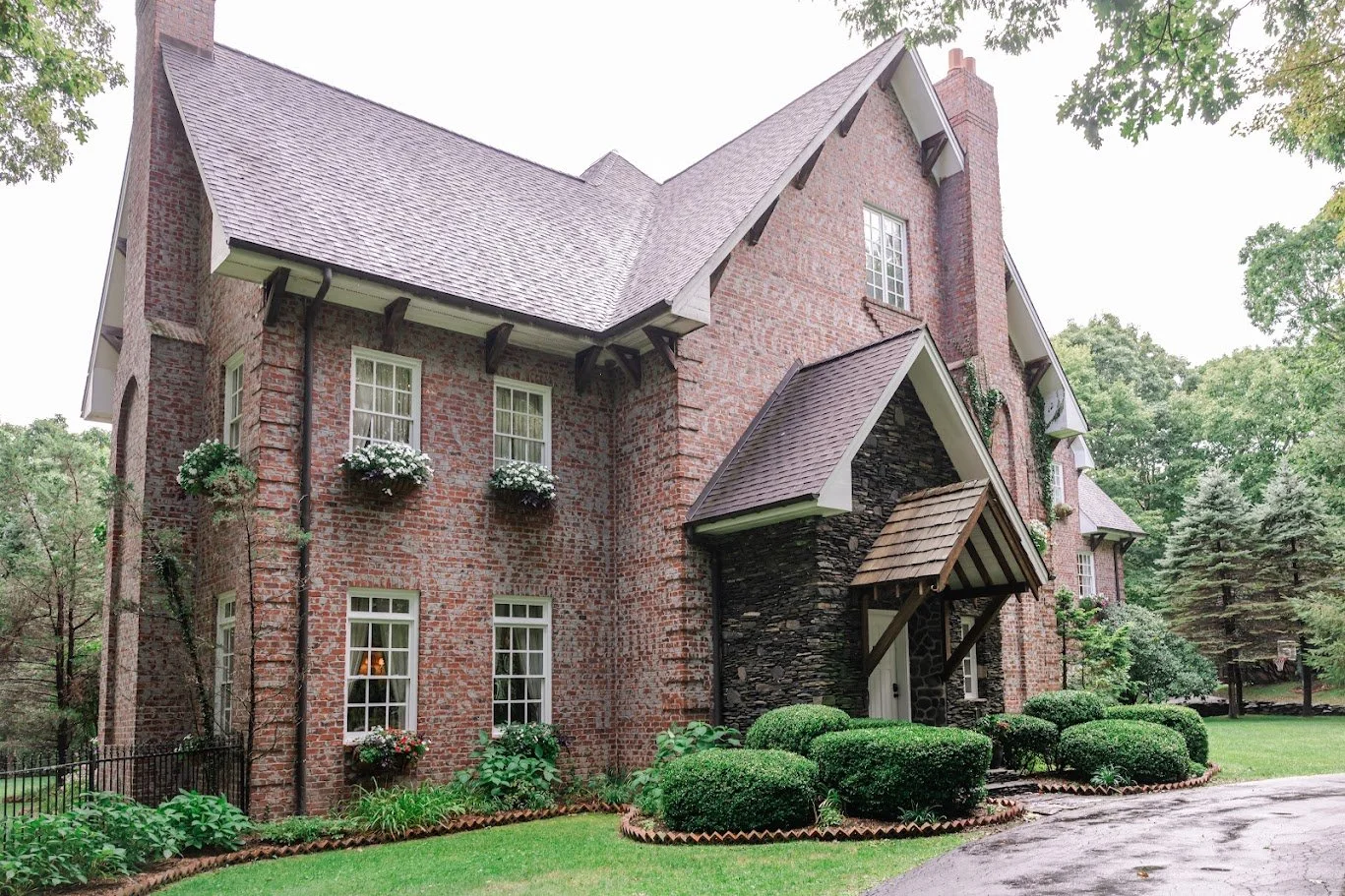 Brick estate wedding venue exterior with steep gables, tall chimneys, and landscaped greenery
