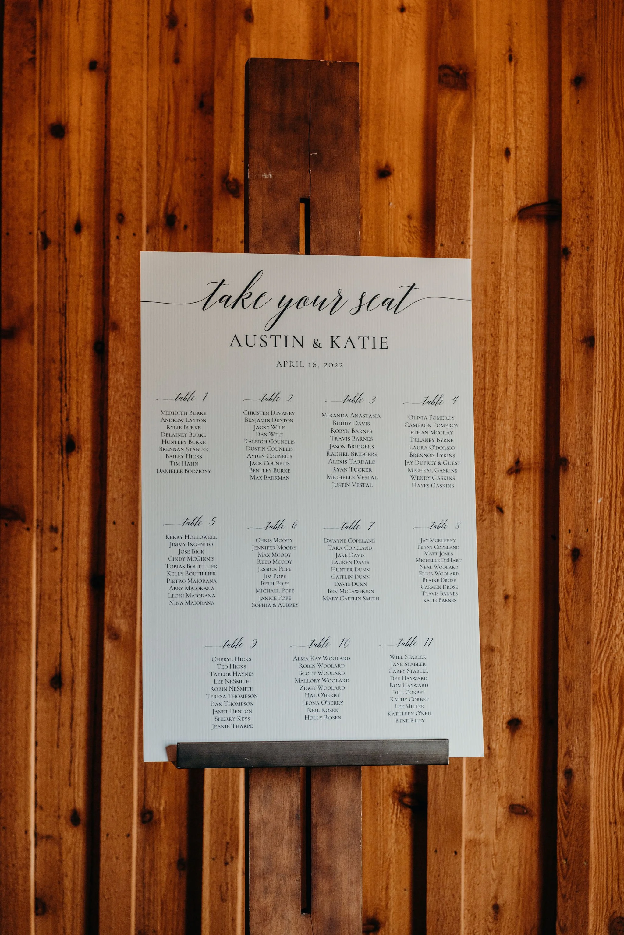 Wedding seating chart sign that reads “Take your seat” for Austin and Katie on a wooden wall.