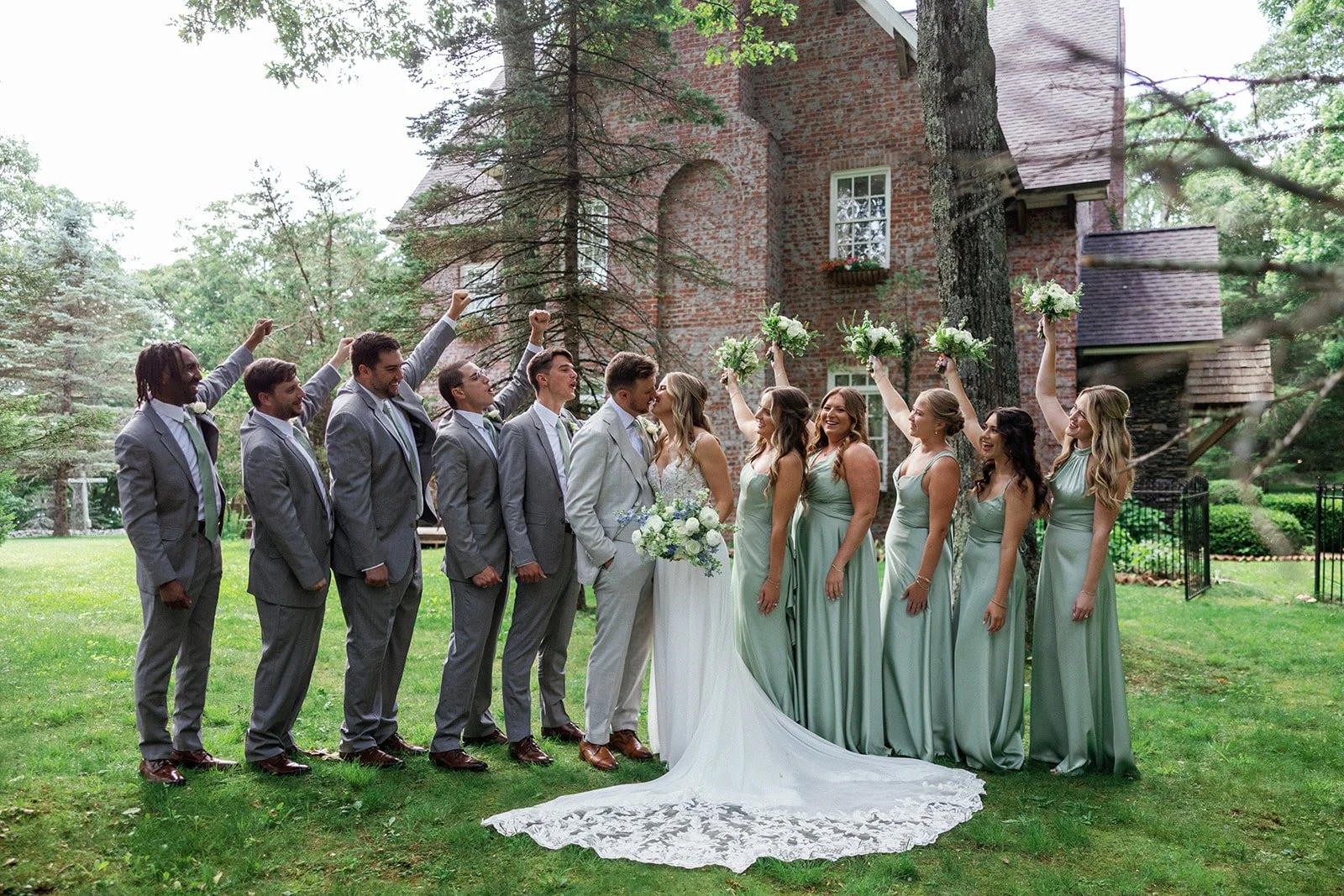 Bride and groom standing with bridesmaids and groomsmen outside a brick estate wedding venue.