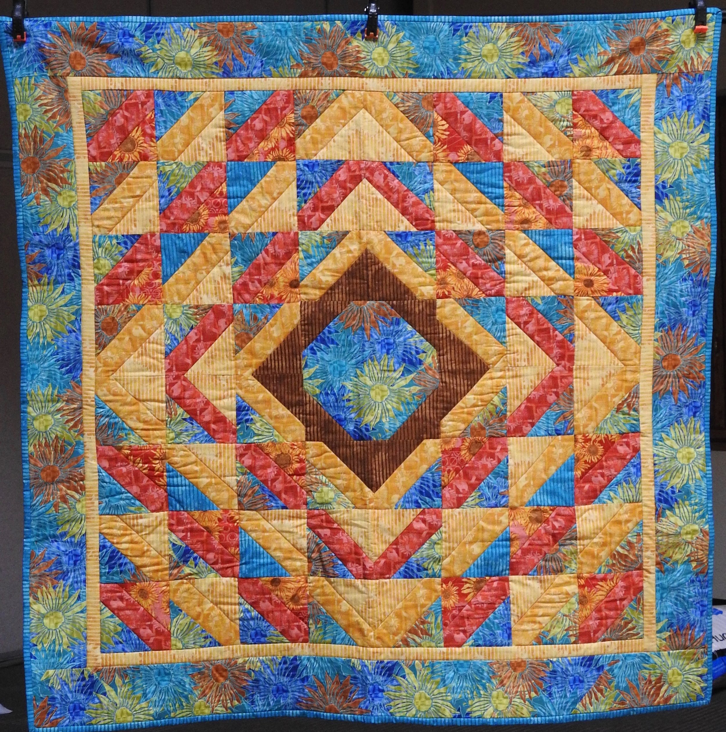 Southern Sunset, Pieced by Jean Mann Graber, Custom Machine Quilted, donated by The Cal Graber Family, 49 x 49”