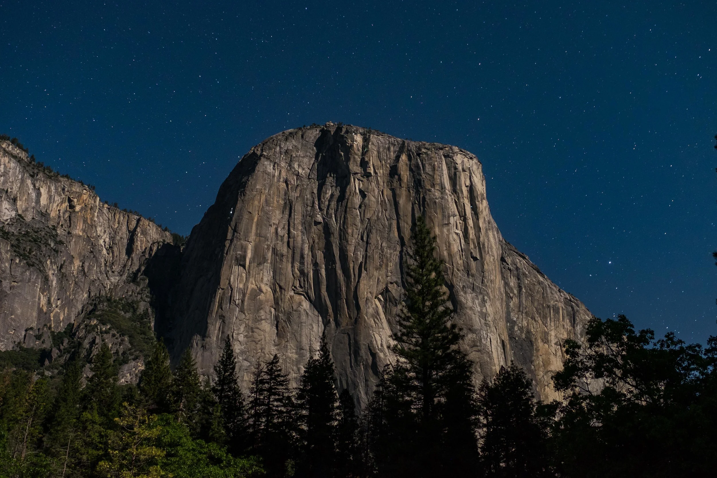 Yosemite's El Capitan at night. If you look closely, you can see climbers bivied up (i.e., sleeping in suspended sleep compartments) on the sheer face of the rock formation illuminated by small lanterns. 