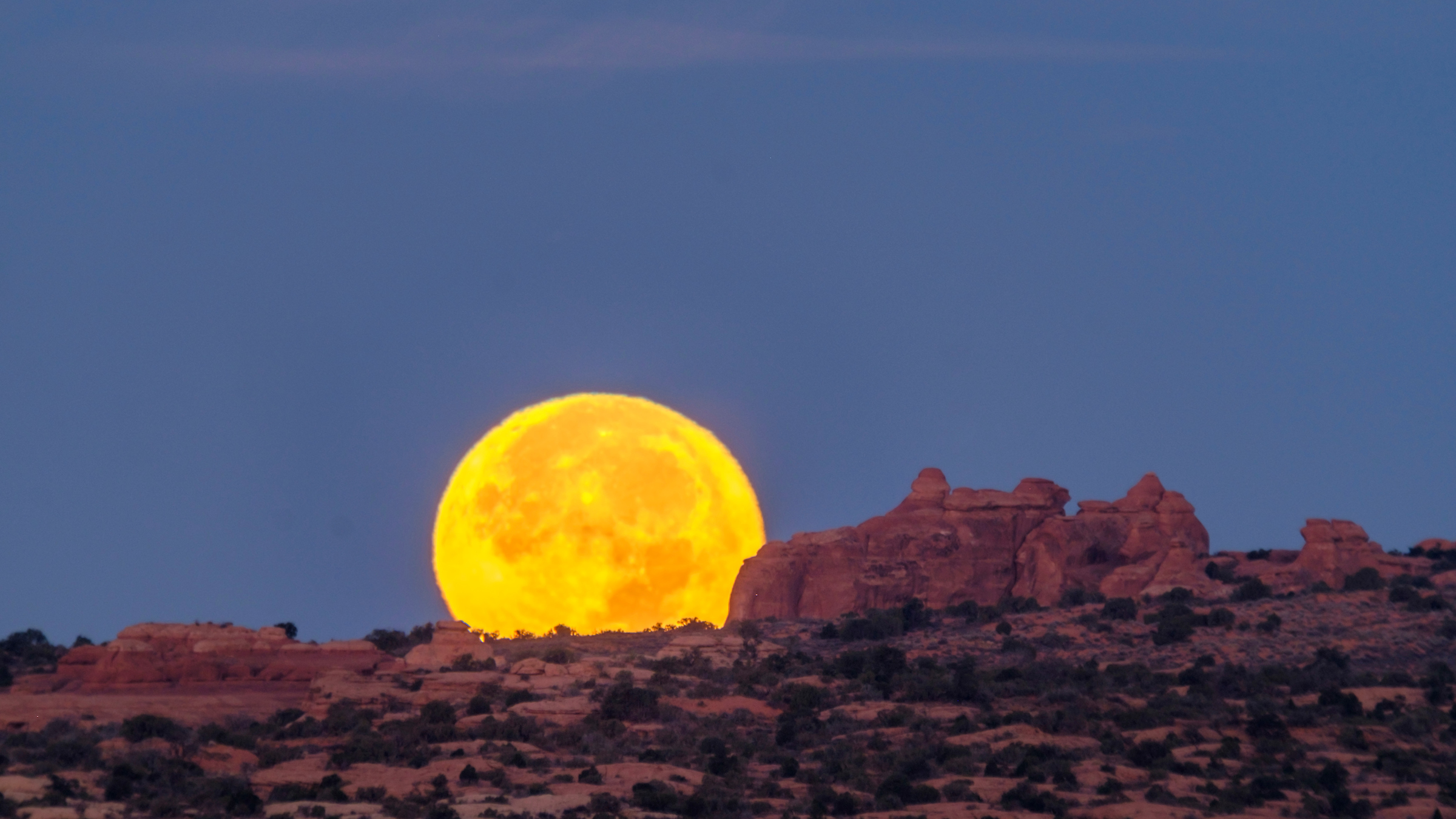 A November 2016 supermoon hugs the horizon in Arches National Park.