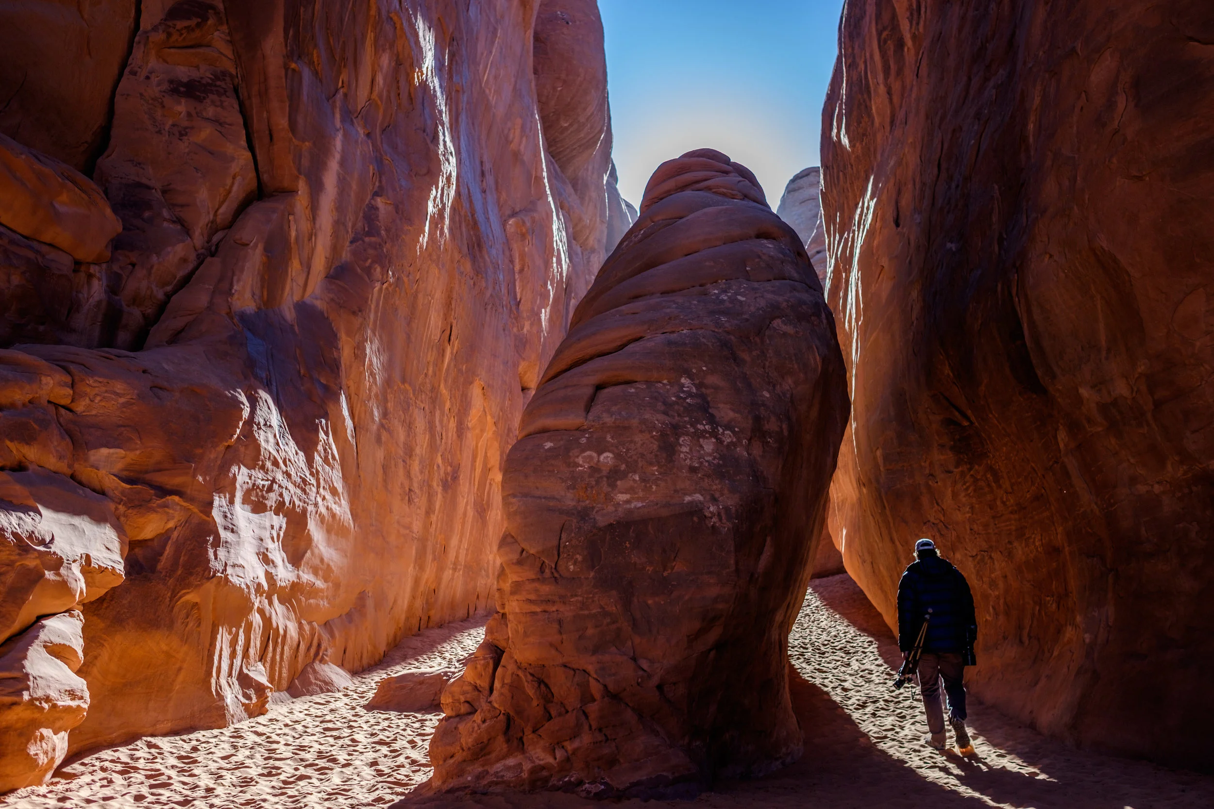 Jonathan walking inside of sandstone fins to Sand Dune Arch.