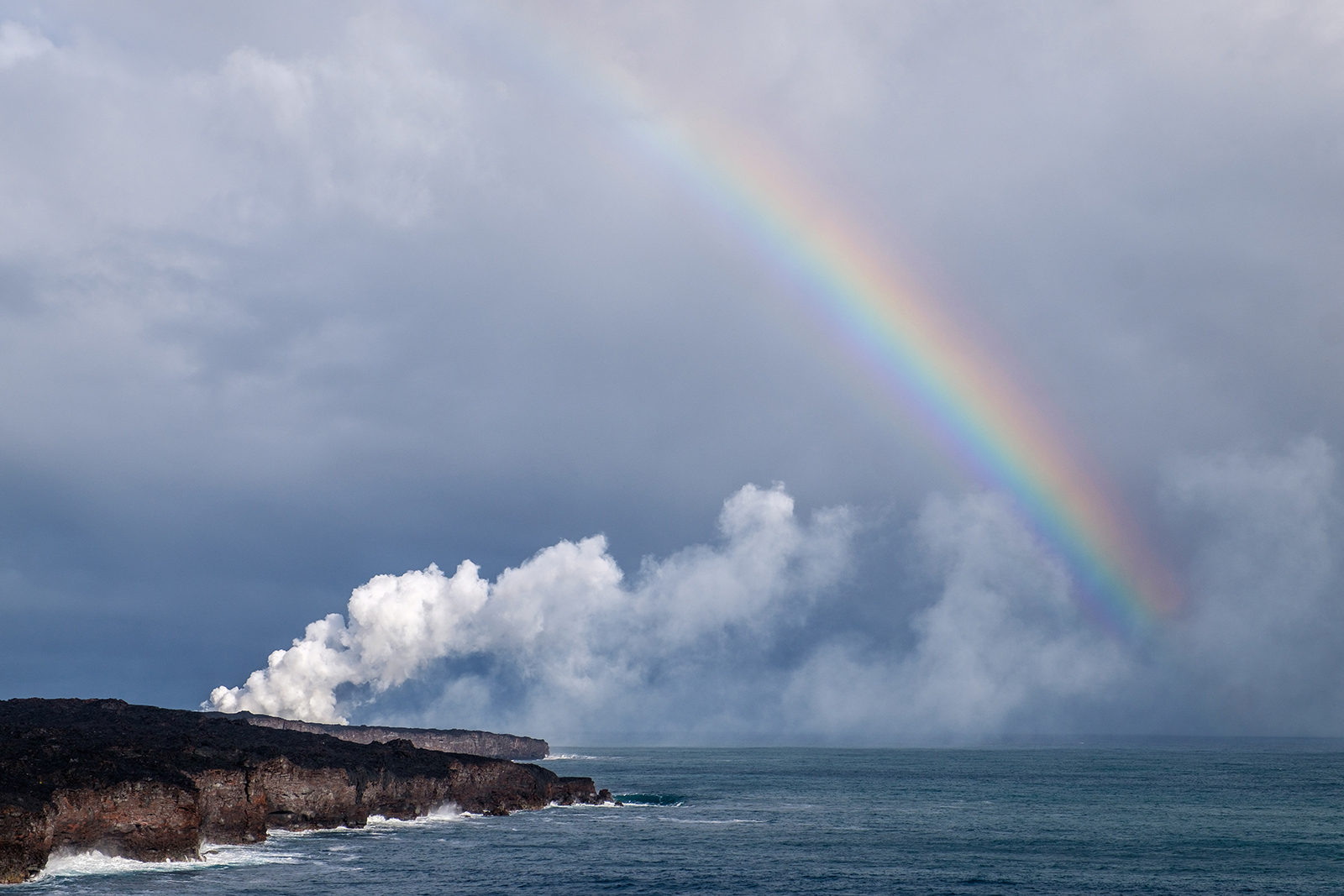A steam cloud rises from where lava from Kīlauea meets the Pacific Ocean...