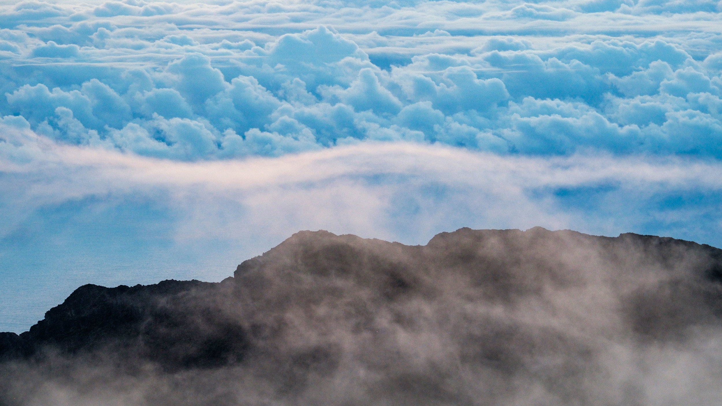 Sunrise view of the clouds hugging the crater atop Haleakala summit in December, 2016. 