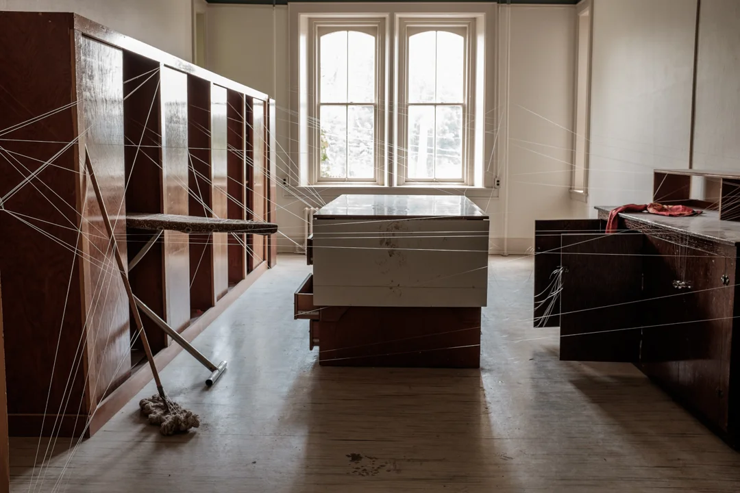 In another room, monofilament, thin as memory, stitches the closets and cabinets into a frantic web, connecting every corner, holding the room in suspension. The transparent threads trace lost passages through the space, barring its use. Mary Zompetti creates a space to which there is no returning; who are we, standing in the doorway?