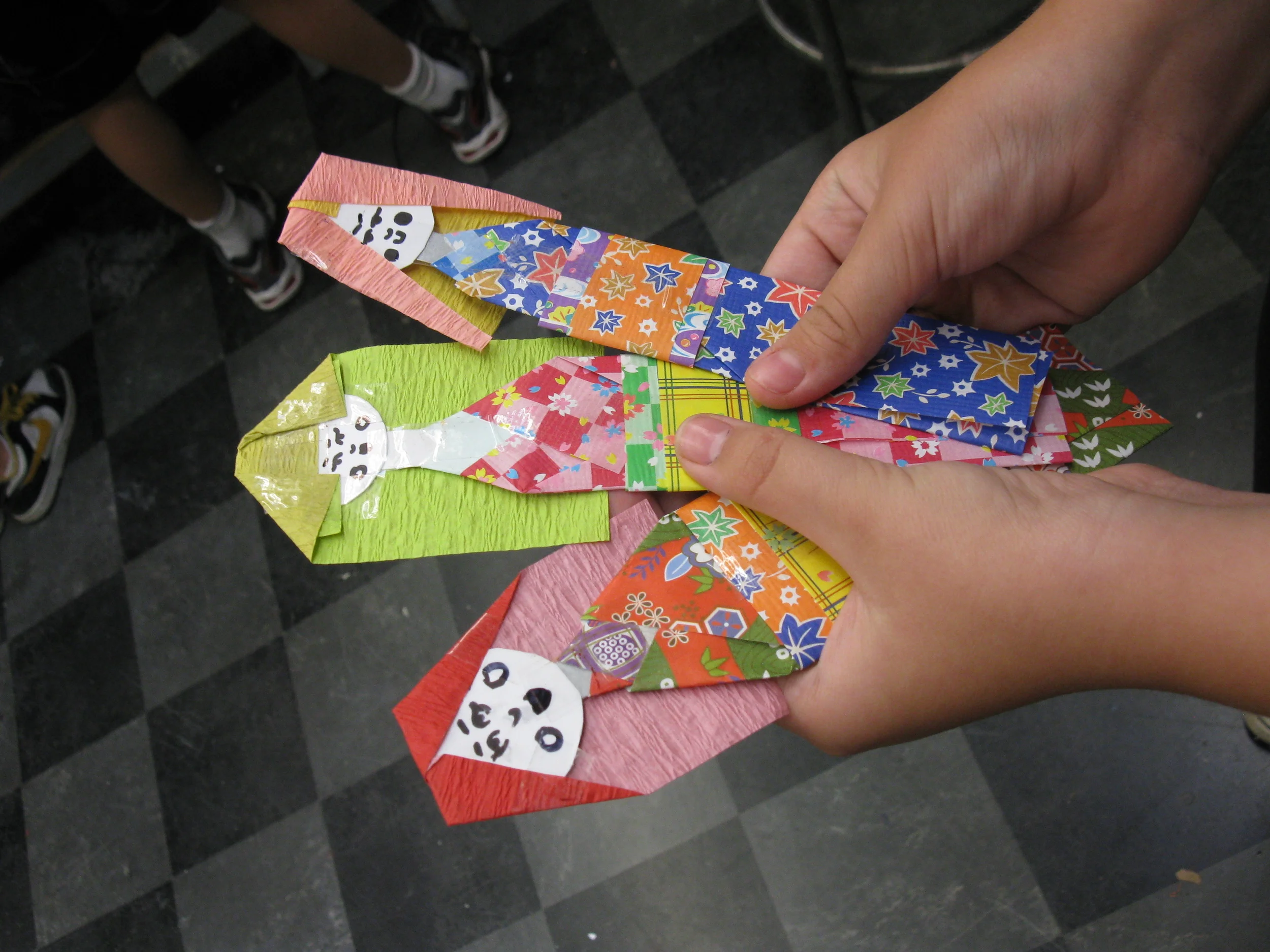  Materials: Decorative paper, glue, tape, markers. Art: Japanese paper dolls, using oragami techniques. Artists: School aged. 