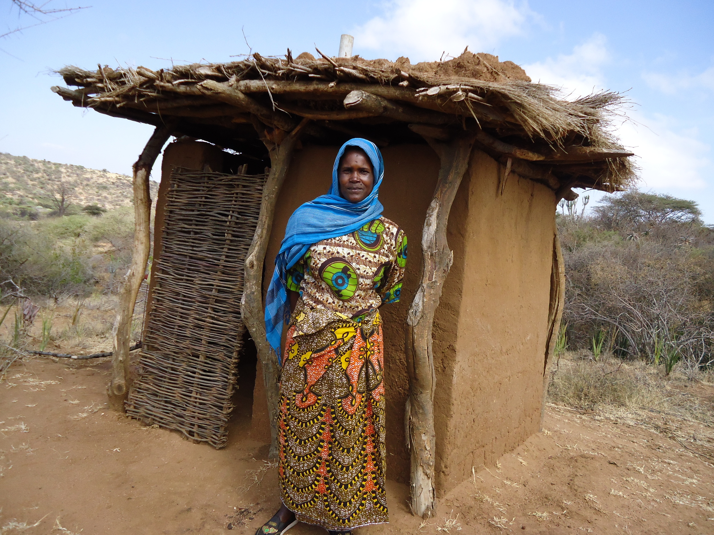 Woman standing outside her new toilet, WaterAid