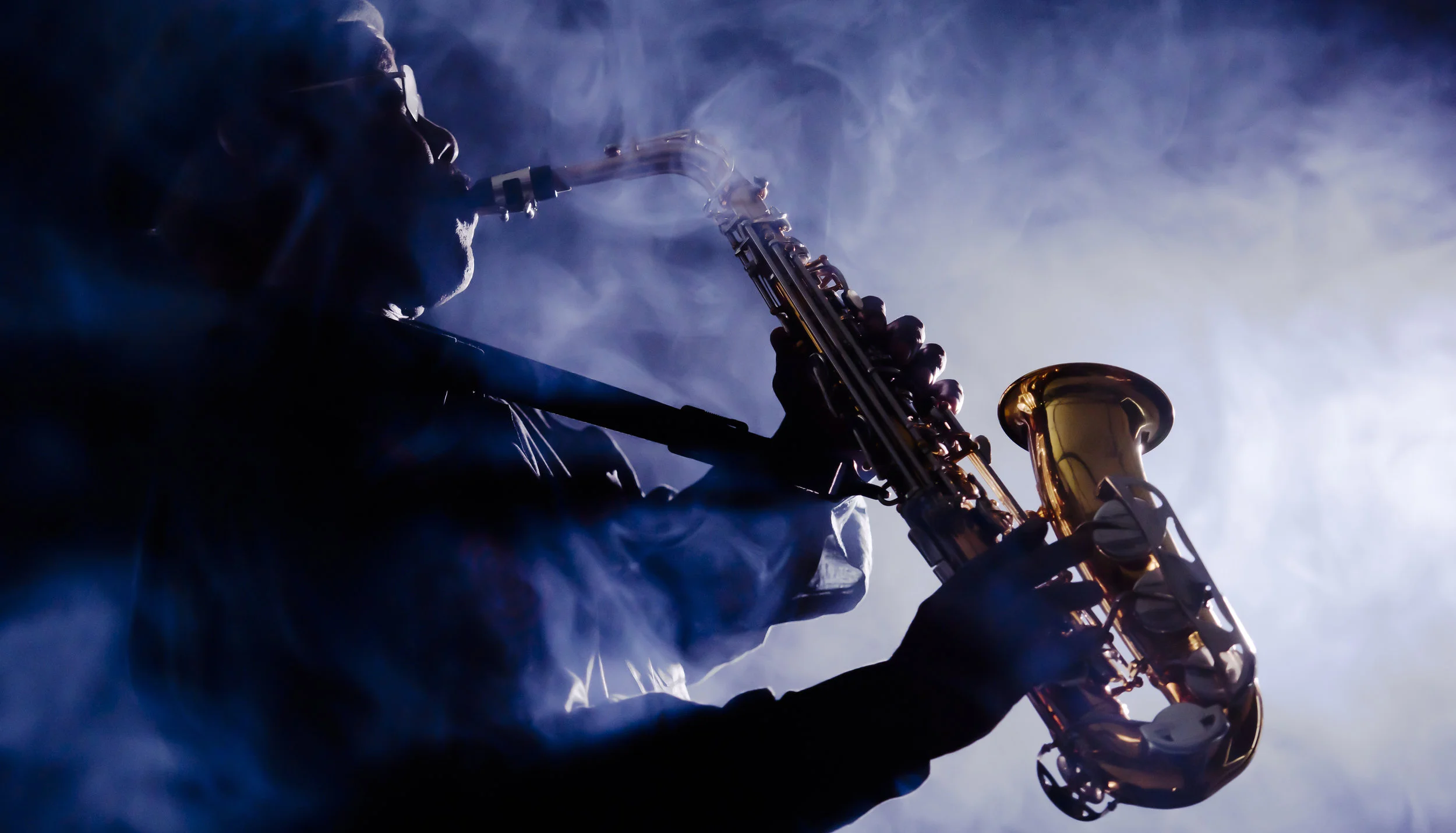 male african american jazz musician playing the saxophone in the blue light and mist 4000px 257064301.jpg