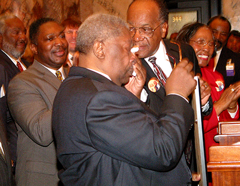 An emotional King is surrounded by Mississippi legislators in Jackson, Miss. as he is presented with a concurrent resolution naming Feb. 15, 2005, as B.B. King Day. (Photo credit: Mississippi Blues Commission)