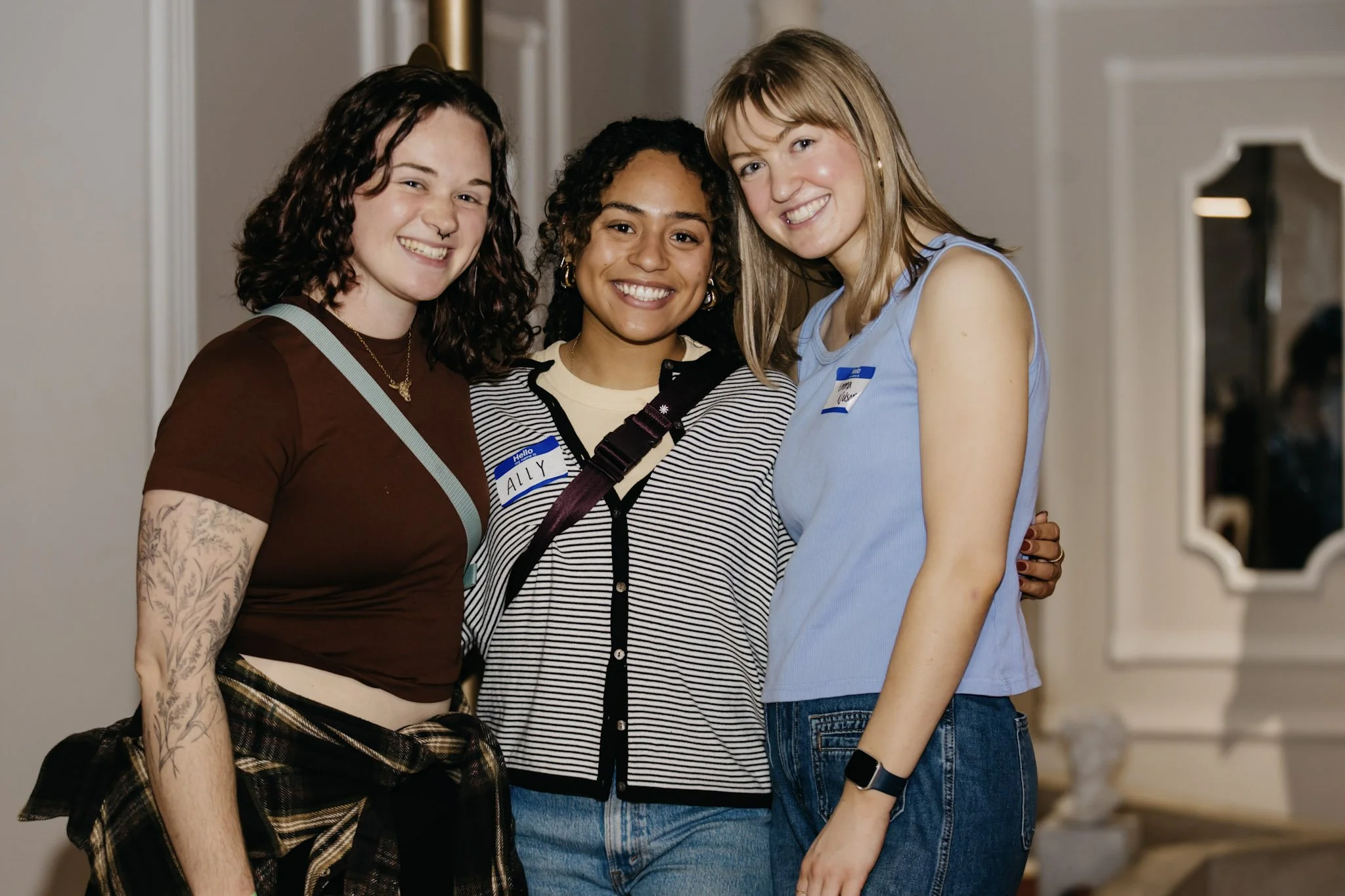 A group of three young people smiling at the camera.