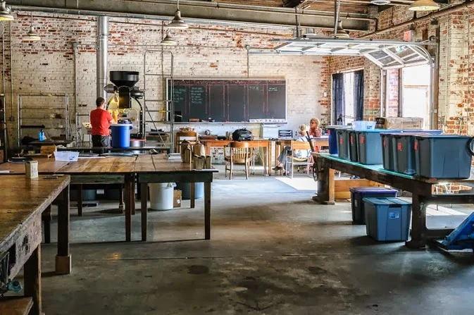The complete renovations, with (from left to right) the large factory table / espresso bar, our long reclaimed heart pine tables with Victorian porch wood trim, long reclaimed wood tables, and our massive industrial L-beam table with salvaged stunning shattered glass tabletop. 