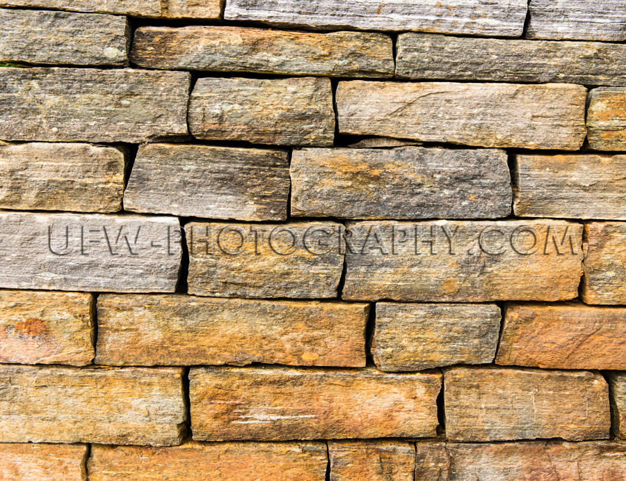 Golden gray stone wall blocks stacked full frame background Stoc