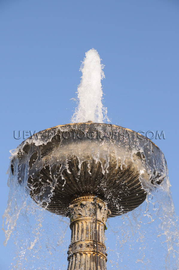 Goblet shaped fountain blue sky close up bubbling water full fra
