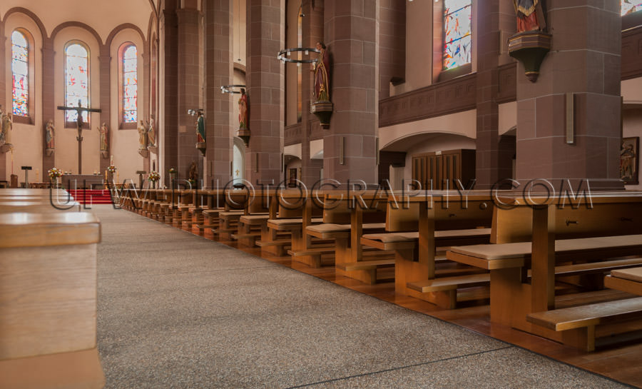 Inside church view rows benches aisle altar cross saint statues 