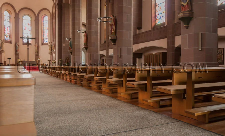 Inside church view rows benches aisle altar cross saint statues