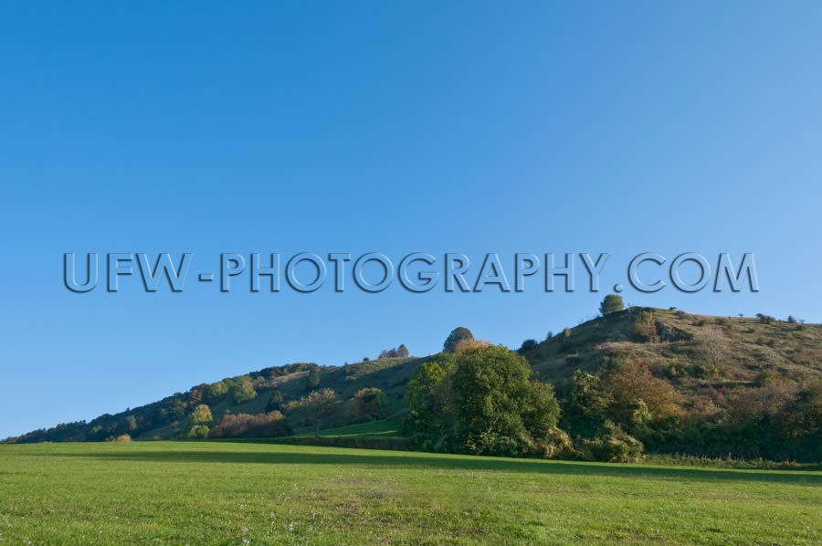 Gently rising hilly Landscape in autumn, against blue Sky - Stoc