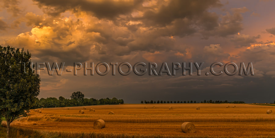 Autumn brown stubbles hay bales harvested field dark stormy sky 