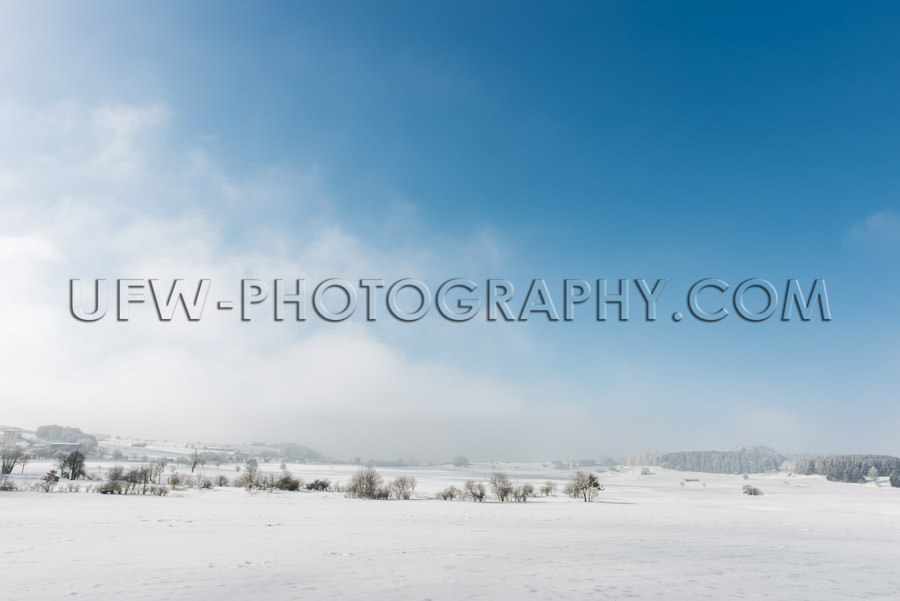 Idyllic winter scene snowy countryside trees blue cloudy sky Sto