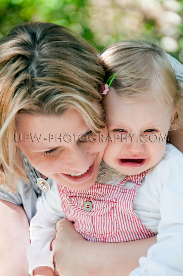 Crying one year old sad girl child comforted loving mother Stock