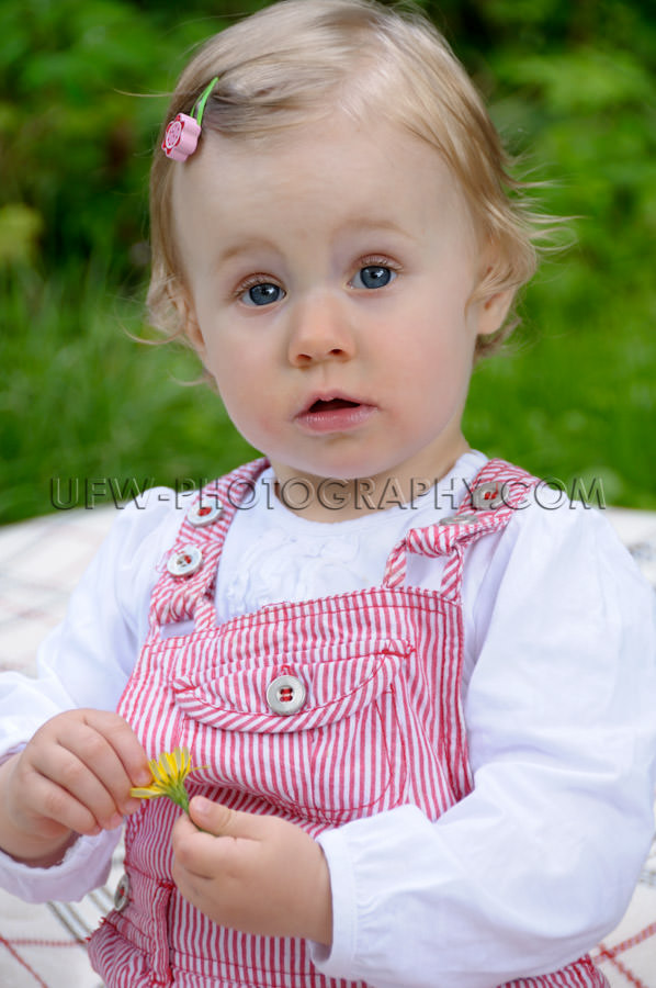 Cute little girl sitting garden dandelion flower looking camera 