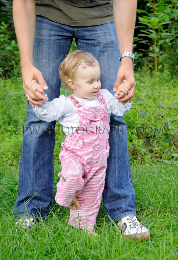 Cute little girl toddler learning walk father hand garden Stock 