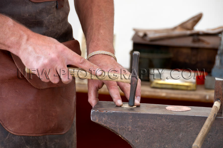 Goldsmith hammering human hand anvil flat sheet metal Stock Imag