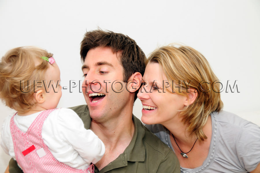 Happy young family of three smiling father mother toddler Stock 