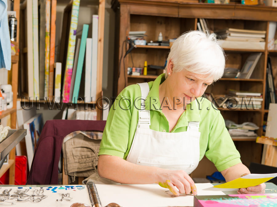 Mature woman sitting desk artist sketching art studio Stock Imag