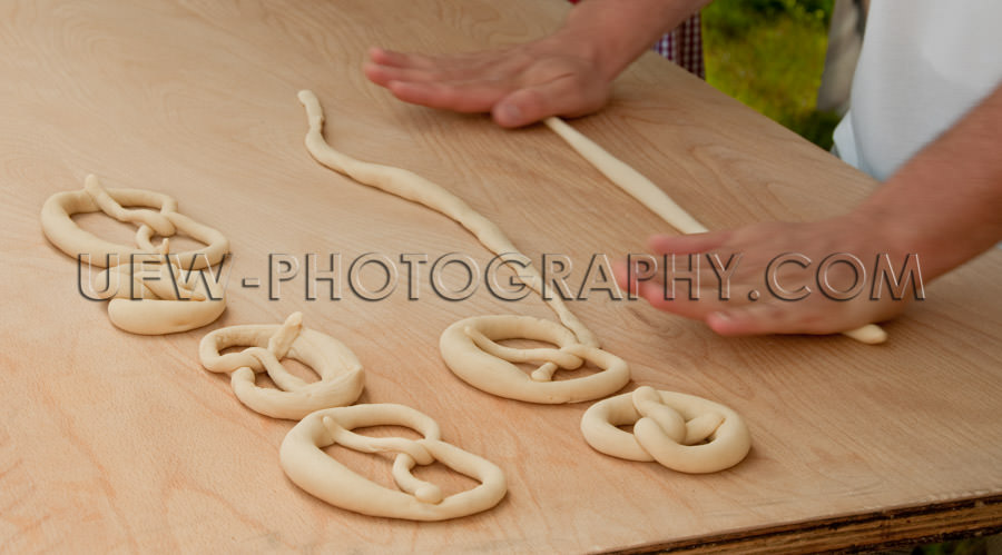Pretzel making hands roll raw dough wooden table close up Stock 