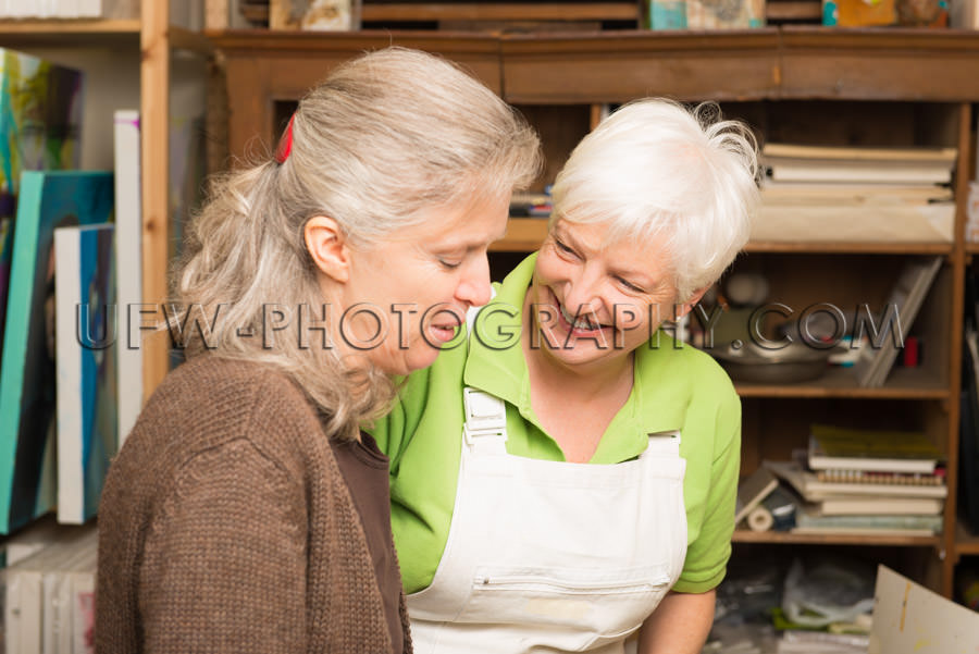 Two mature women talking gray hair art studio Stock Image