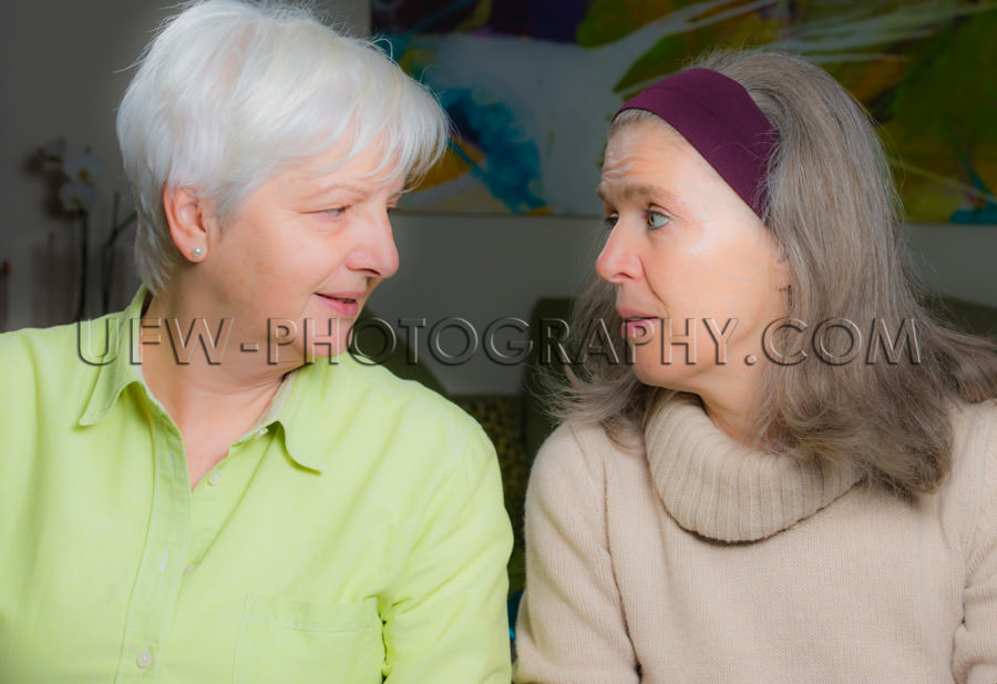 Two mature women talking looking face to face conversation Stock