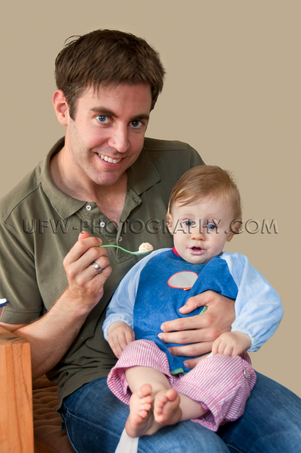 Young father feeding one year old girl toddler sitting laps Stoc