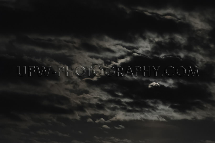 Full moon partly visible clouds dark moody mysterious night sky 