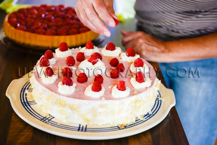 Decorating delicious raspberry cream cake kitchen woman hand Sto