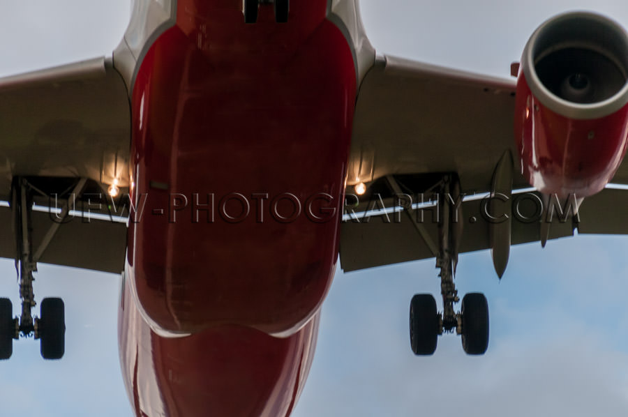 Airplane landing close-up from below silver red Stock Image