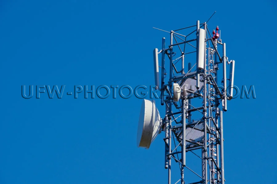 Mobile phone antenna close up against deep blue clear sky Stock
