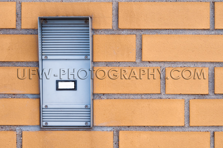 Rubust industrial door intercom, built into a yellow brick wall 