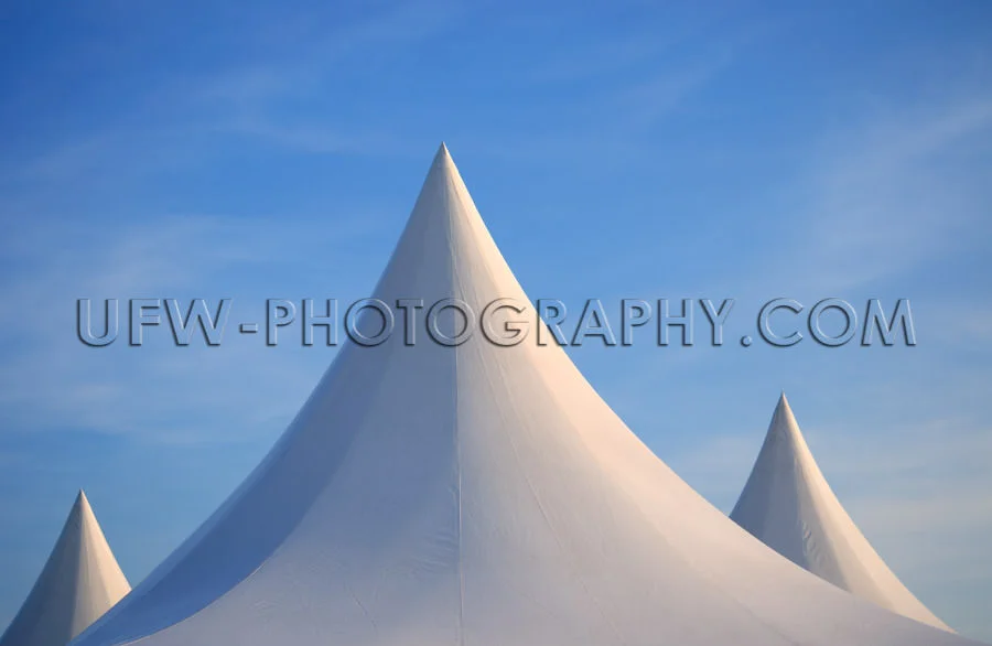 Three white spiked tent tops against deep blue sky Stock Image
